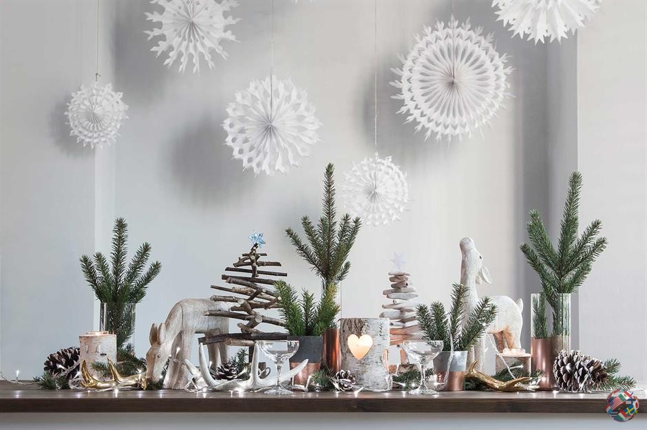 Поддержите минимализм в скандинавском стиле и создайте потрясающую демонстрацию огромных бумажных снежинок с множеством замысловатых дизайнов. Повесьте их с потолка над праздничной картиной из светодиодных свечей, гирлянд, листвы и сосновых шишек. Завершите сцену милыми деревянными украшениями.
